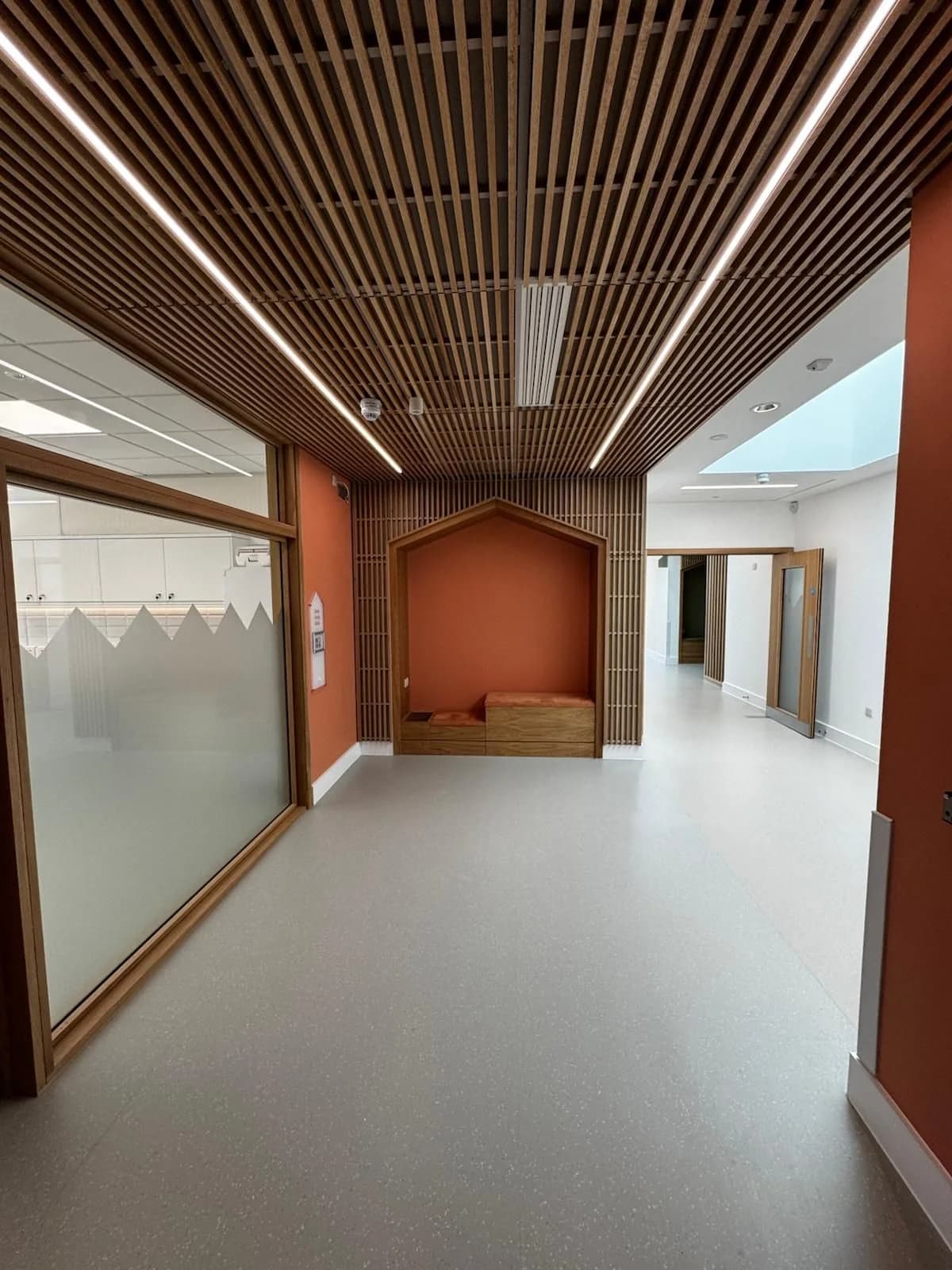 Finished circulation space with timber slat ceiling and orange walls